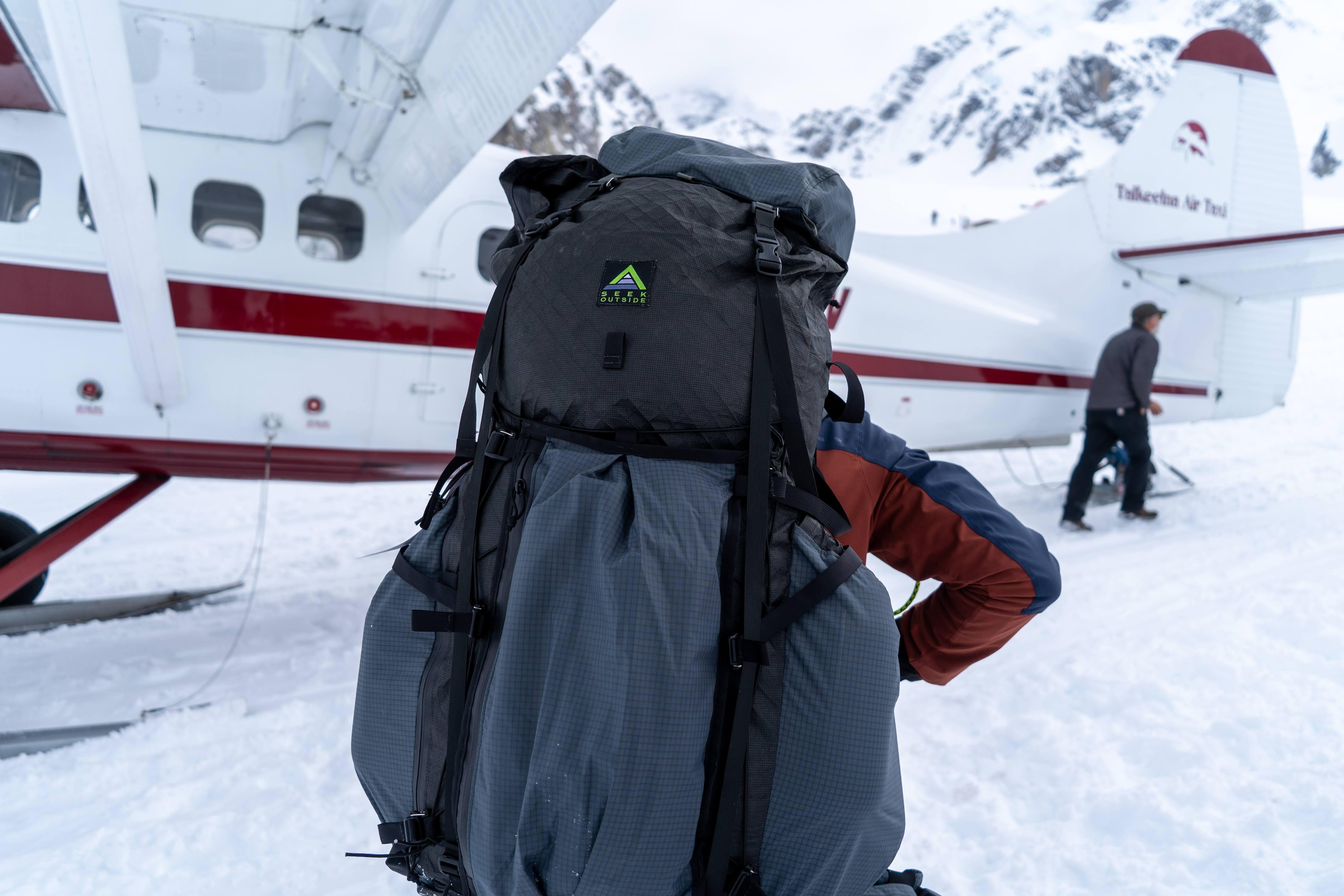 A backpack and bush plane parked on a snowy tundra, ready for a mountaineering expedition