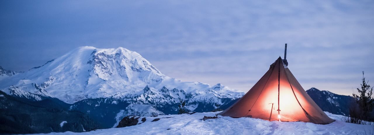 winter camp, tipi pitched in snow with vast mountain view